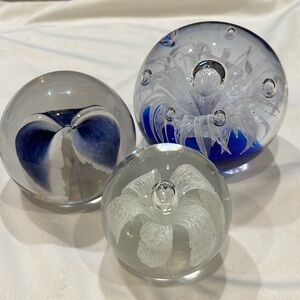 3 glass paperweights with blue and white floral design and controlled bubbles